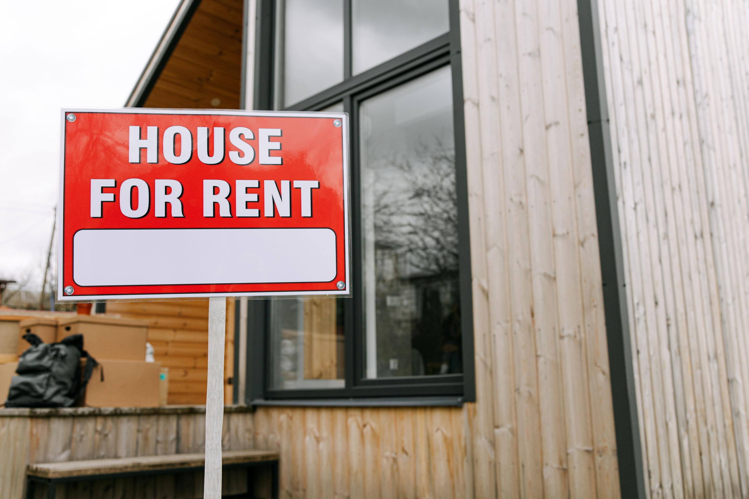 A βFor Rentβ sign displayed outside a wooden house