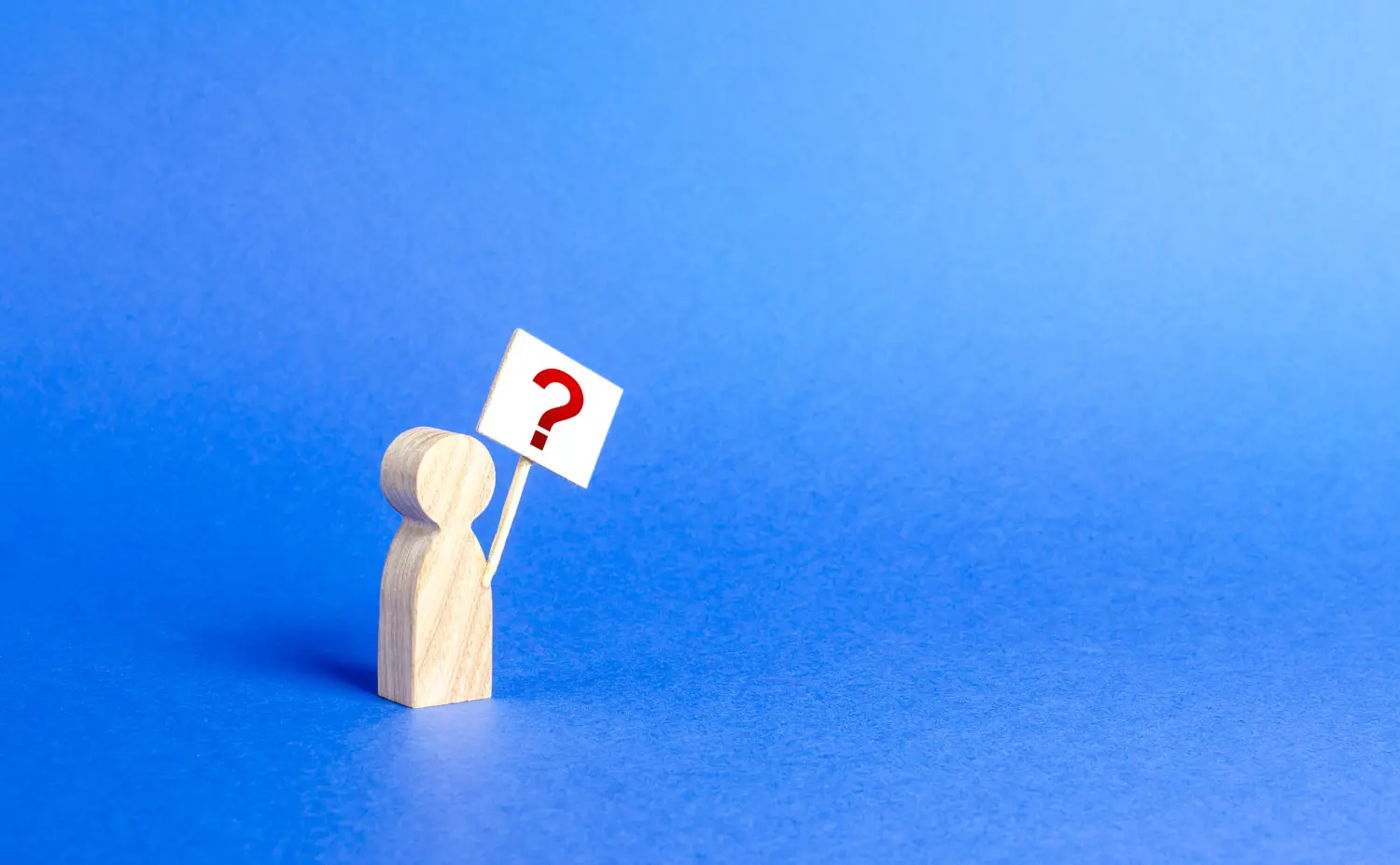 A wooden figure holding a sign with a red question mark