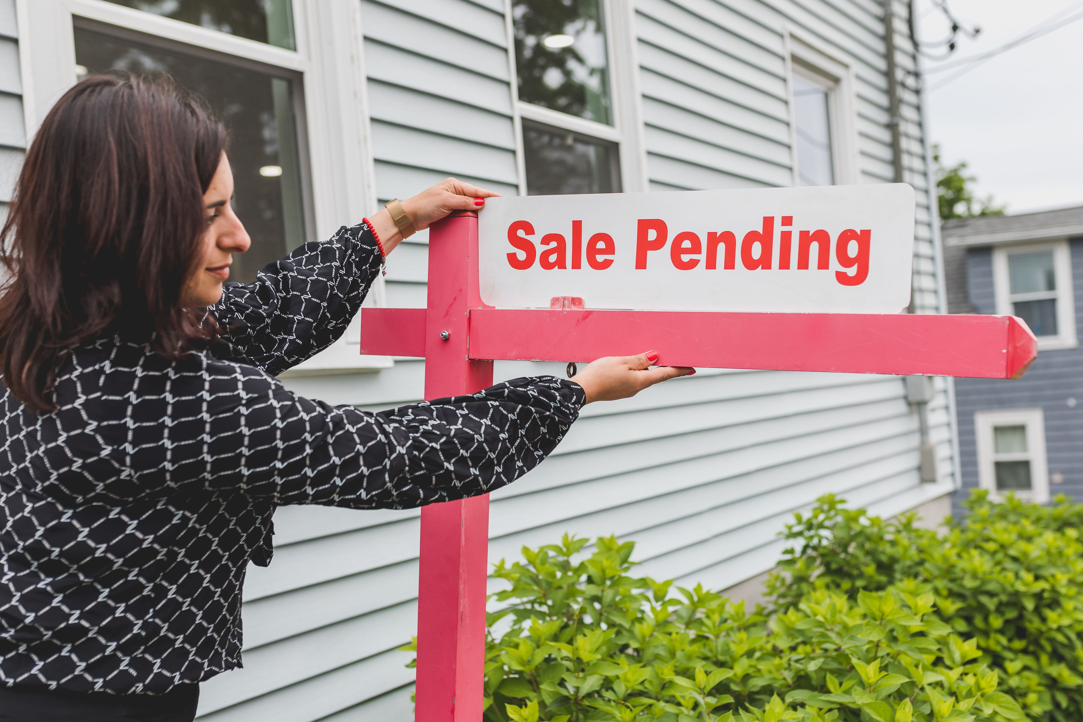 A “Sale Pending” sign is placed in front of a house by a realtor