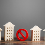 Wooden house figures on either side of a red prohibition sign