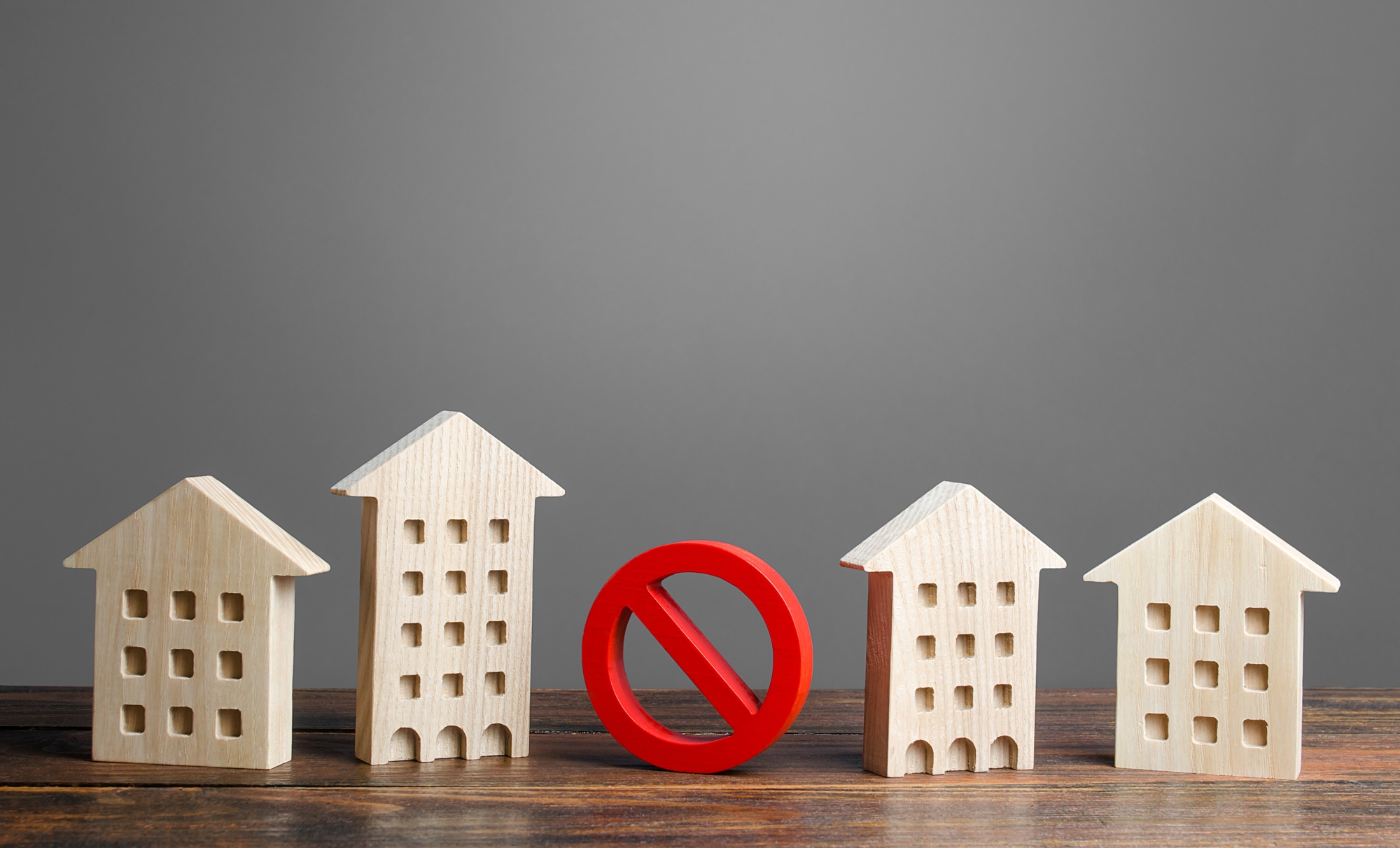 Wooden house figures on either side of a red prohibition sign