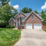 A large brick home with a double garage and a curved driveway