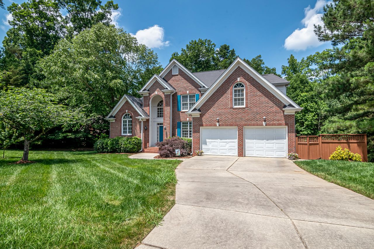A large brick home with a double garage and a curved driveway