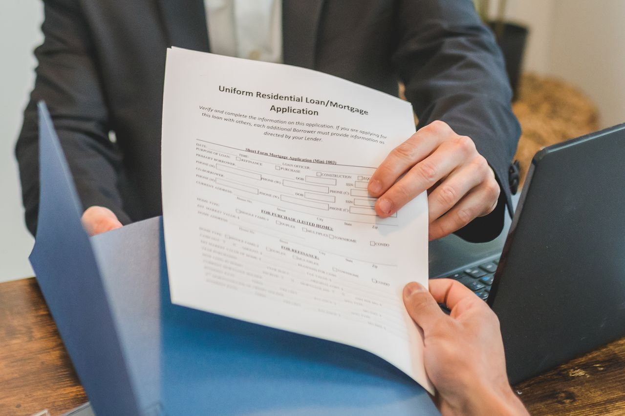 A loan officer hands a potential home buyer a mortgage loan application