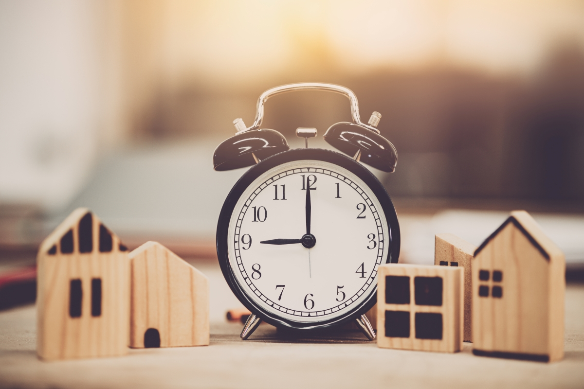 An alarm clock between two sets of wooden house figures