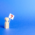 A wooden figure holding a sign with a red question mark