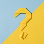 A yellow origami question mark on a diagonal two-tone background in yellow and light blue