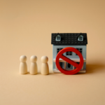 A house figure with a red prohibition sign in front of it and three wooden figures to the left