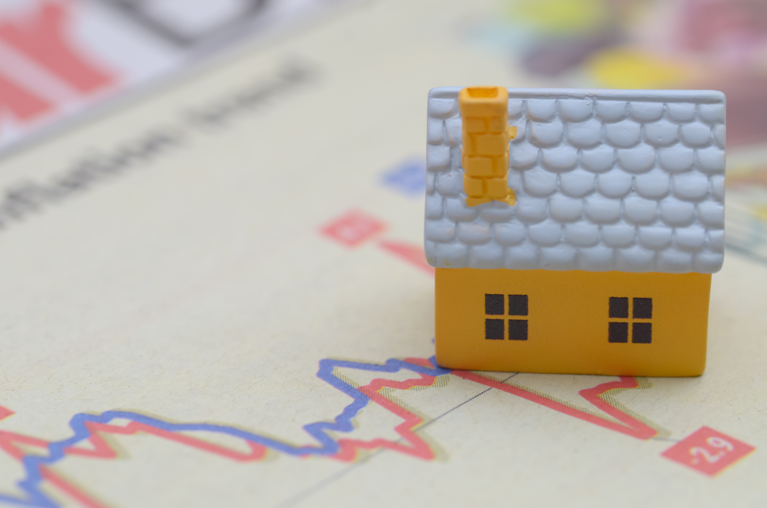 A small house figurine atop a housing market graph